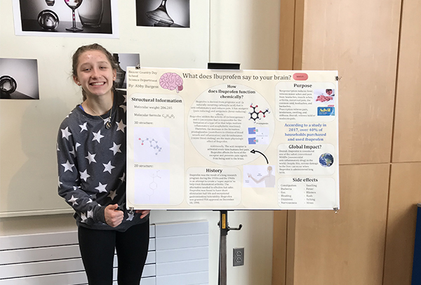 A student standing with her poster